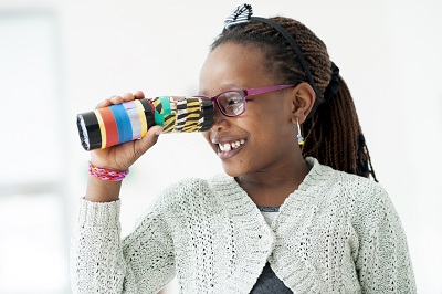 a girl looks through a homemade kaleidoscope