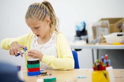 A girl using scissors on colourful tape