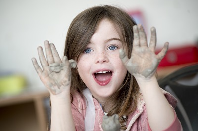 girl with clay covered hands